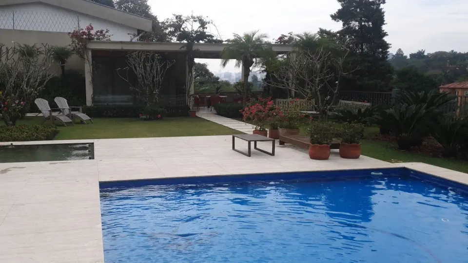 Piscina azul e limpa num jardim, atendida pela Vinícius Piscinas